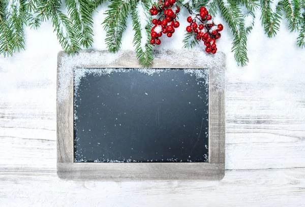 Kerst decoratie groenblijvende boom tak rode bessen chalkboar — Stockfoto