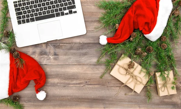 Lugar de trabajo portátil Navidad decoración rojo sombrero regalos plana laico — Foto de Stock