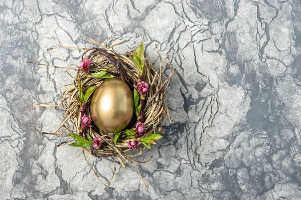 Золотые пасхальные яйца в птичьем гнезде с цветами — стоковое фото