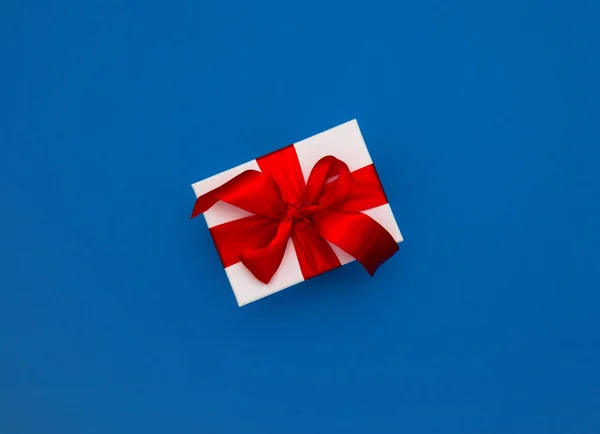 Κουτί δώρου κόκκινη κορδέλα τόξο κλασικό μπλε φόντο — Φωτογραφία Αρχείου