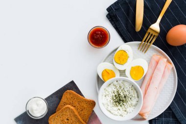 Sağlıklı kahvaltı. Haşlanmış yumurta, jambon ve taze peynir serpilir w
