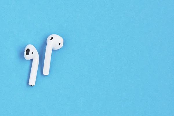 Fehér vezeték nélküli fülhallgató kék háttérrel. — Stock Fotó