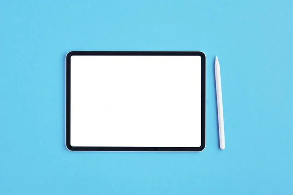 Tableta con lápiz blanco sobre fondo azul . — Foto de Stock
