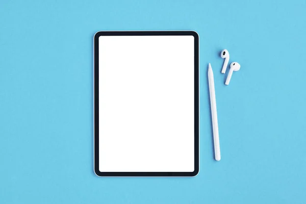 Tablet with pencil and earphones on blue background. — Stock Photo, Image