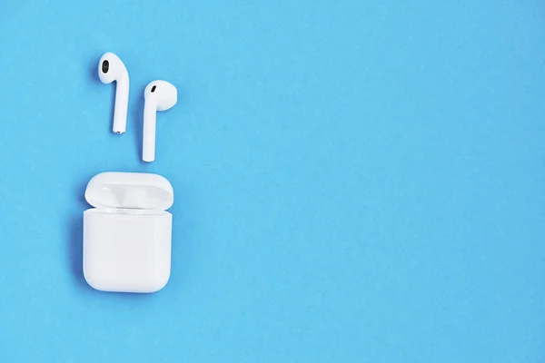 White wireless earphones on blue background. — Stock Photo, Image