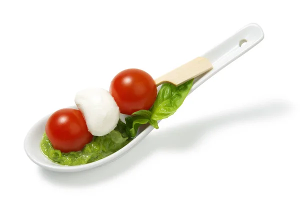 Salada Caprese em paus com molho de pesto em uma colher cerâmica em um fundo branco — Fotografia de Stock