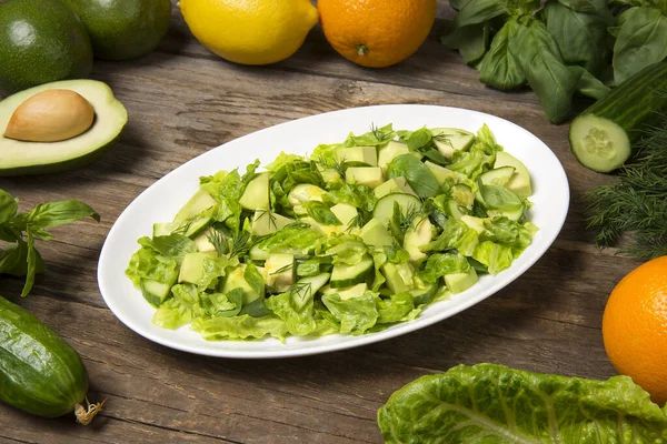 Turunçgil salatalı yeşil salata, yeşil salatalık yeşil fasulye ve kırsal bir masada oval bir tabakta romaine salatası. Seçili odak.