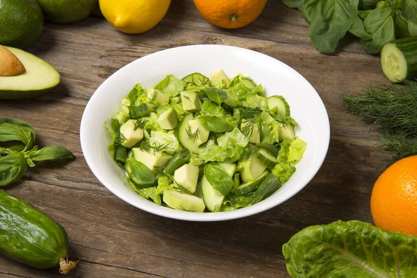 Turunçgil salatalı salata, avokado salatalıklı yeşil fasulye ve kırsal ahşap masada bir kasede romaine salatası. Seçili odak.