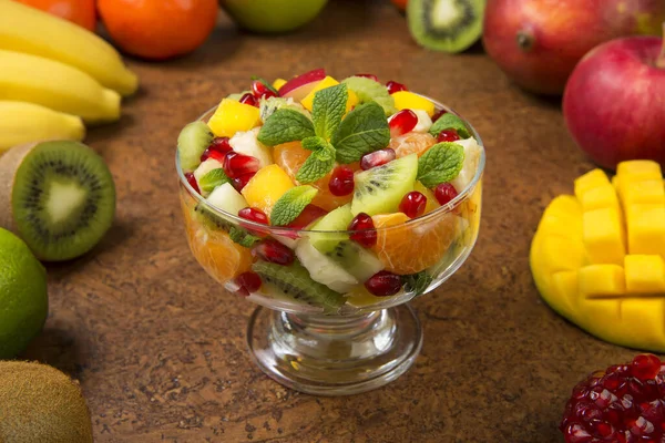 Kahverengi bir masada taze malzemelerle dolu cam salata kaselerinde meyve salatası. Seçili odak.