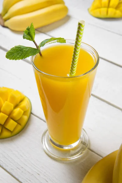 Freshly mango juice with bananas and mint with Ingredients on a old white table. Selected focus.