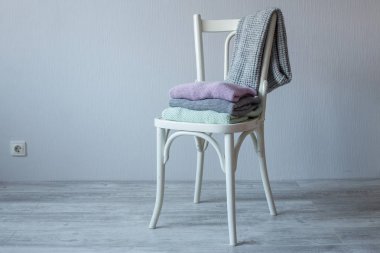 Bir tahta sandalyede rahat örme elbise yığını.