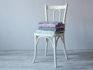 Bir tahta sandalyede rahat örme elbise yığını.