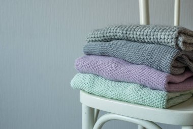 Bir tahta sandalyede rahat örme elbise yığını.