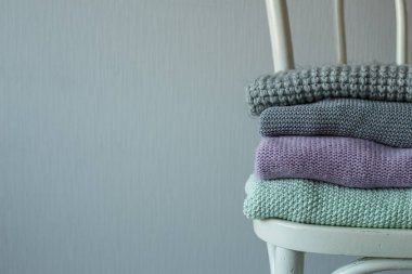 Bir tahta sandalyede rahat örme elbise yığını.