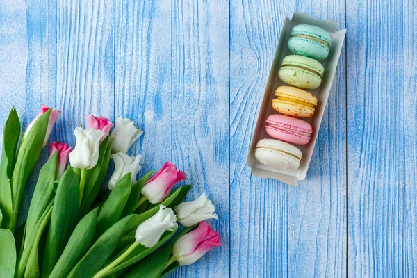 Tulips with macaroons on blue wooden background — Stock Photo, Image