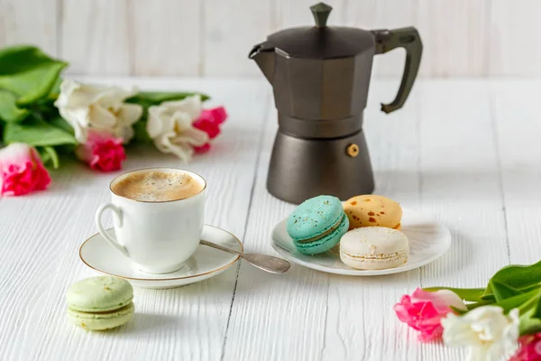 Kaffee, rosa und weiße Tulpen und Macarons auf dem weißen Holztisch — Stockfoto