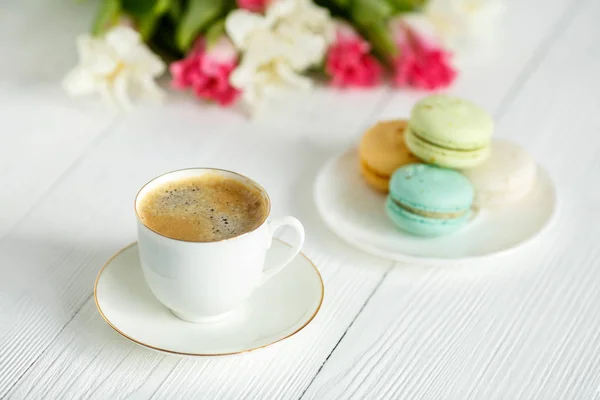 Kaffee, rosa und weiße Tulpen und Macarons auf dem weißen Holztisch — Stockfoto