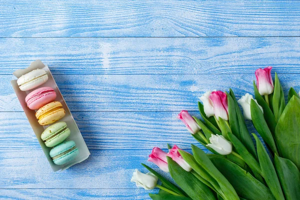 Tulips with macaroons on blue wooden background — Stock Photo, Image