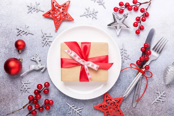 Juego de mesa de Navidad con plato blanco vacío, caja de regalo, cubiertos con decoraciones festivas sobre fondo de piedra — Foto de Stock