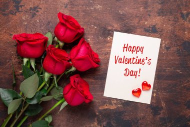 Sevgililer Günü tebrik kartı, üzerinde kırmızı gül çiçekleri olan eski ahşap bir arka plan.