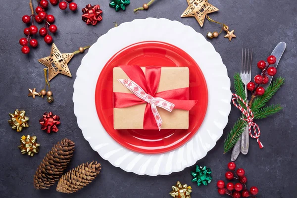 Ajuste de mesa de Navidad con plato rojo, caja de regalo, cubiertos con decoraciones festivas arco de estrella sobre fondo de piedra — Foto de Stock