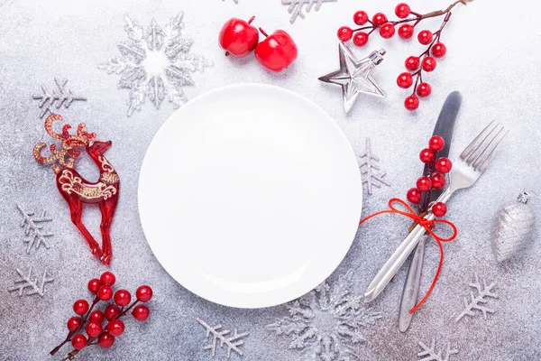 Christmas table place setting with empty white plate, cutlery with festive decorations on stone background — Stock Photo, Image