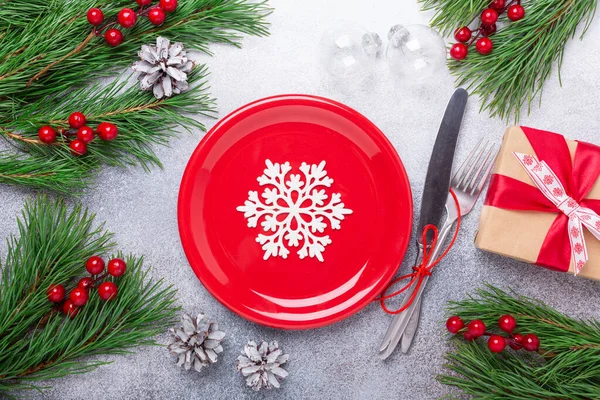 Juego de mesa de Navidad con plato rojo vacío, cubiertos con decoraciones festivas sobre fondo de piedra — Foto de Stock