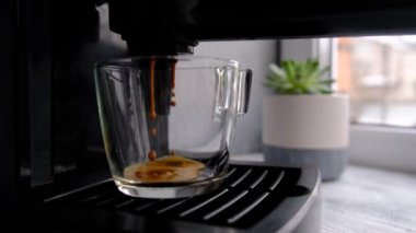 Kahve makinesi cam şeffaf kahve fincanından espresso yapıyor. Sıcak espresso bardağa doluyor..