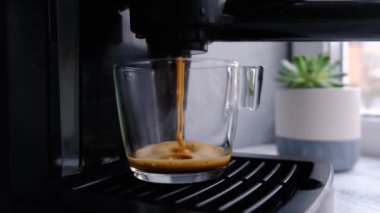Kahve makinesi cam şeffaf kahve fincanından espresso yapıyor. Sıcak espresso bardağa doluyor..