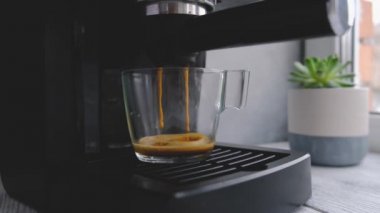 Kahve makinesi cam şeffaf kahve fincanından espresso yapıyor. Sıcak espresso bardağa doluyor..