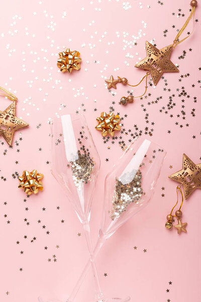 Рождественская квартира. Бокалы для шампанского и золотые украшения на розовом фоне
