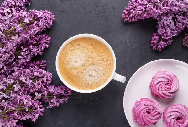 Gałąź liliowa, filiżanka kawy, domowej roboty różowa pianka na czarnym kamiennym tle — Zdjęcie stockowe