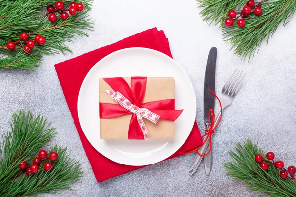 Juego de mesa de Navidad con plato blanco vacío, caja de regalo, cubiertos con decoraciones festivas sobre fondo de piedra — Foto de Stock