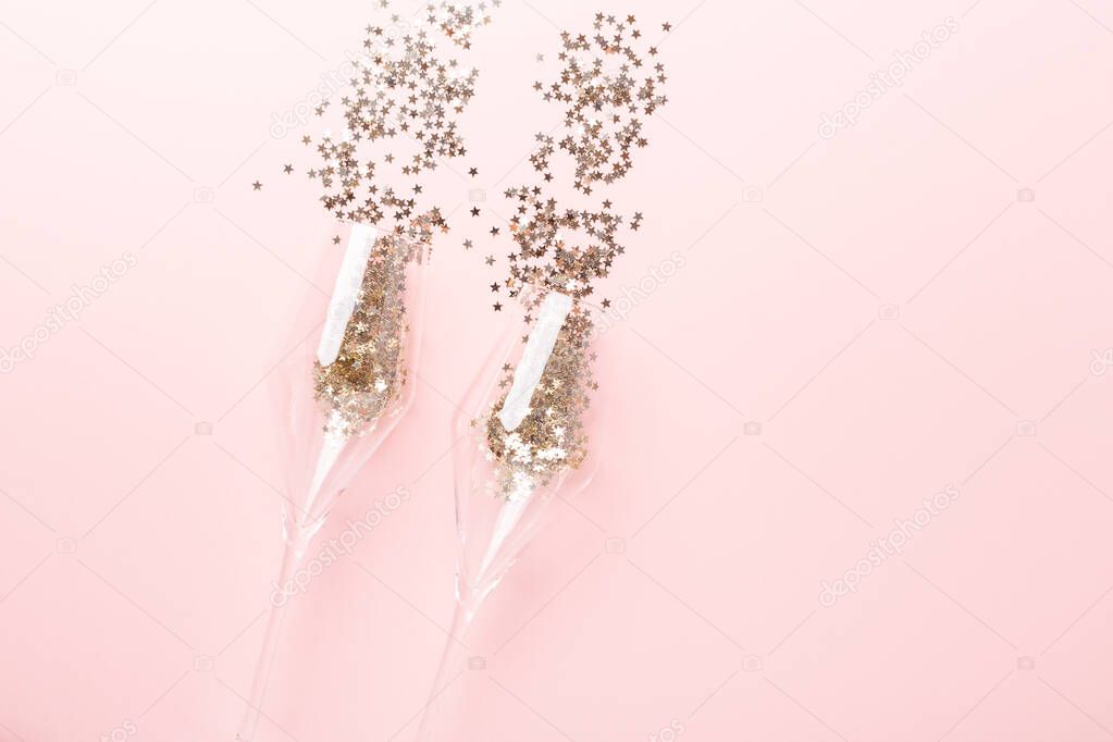 Christmas flat lay. Champagne glasses and gold decoration on pink background