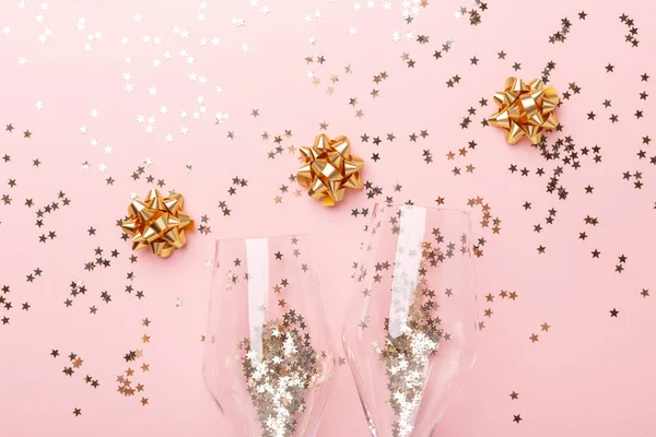 Ett julligg. Champagne glasögon och guld dekoration på rosa bakgrund — Stockfoto