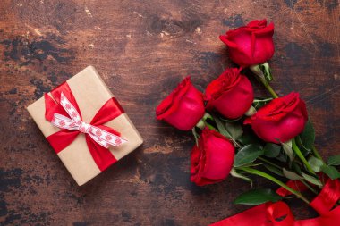 Ahşap arka planda kırmızı güller ve hediye kutusu. Sevgililer Günü tebrik kartı.
