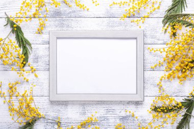 Paskalya dekoru, mimoza çiçekleri ve ahşap masa çerçeveli. Gri çerçeveli bir model. Üst Manzara. Boşluğu kopyala