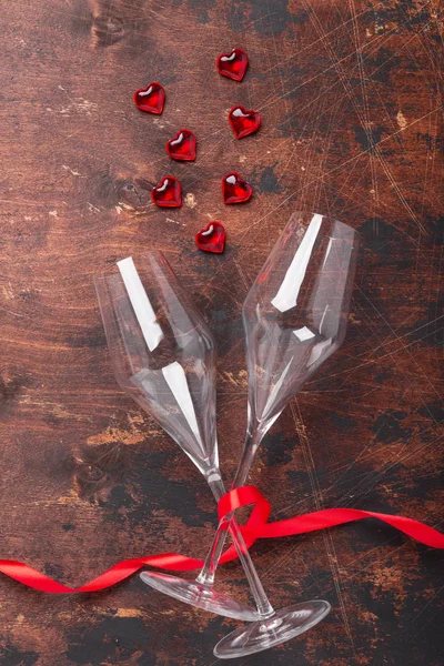 Открытки на день Святого Валентина с бокалами для шампанского, декоративными сердцами и красной лентой на деревянном фоне — стоковое фото