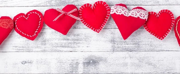 Corazones rojos sobre fondo blanco de madera. El concepto de San Valentín. Banner web. Copia espacio para tu texto — Foto de Stock