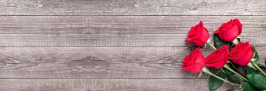 Gri ahşap masada kırmızı güller. Sevgililer Günü tebrik kartı. Üst Manzara. Uzayı kopyala Web pankartı