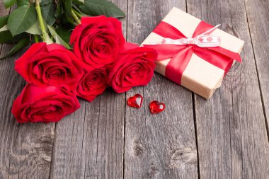 Kırmızı güller ve hediye kutusu gri ahşap masada. Tebrik kartı. Metin için alanı kopyala