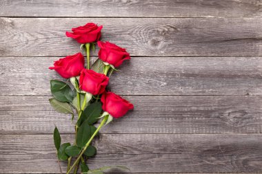 Gri ahşap masada kırmızı güller. Sevgililer Günü tebrik kartı. Üst Manzara. Boşluğu kopyala