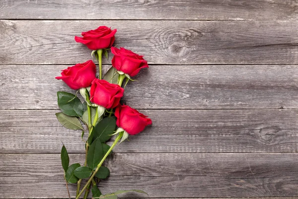 Rote Rosen blühen auf grauem Holztisch. Valentins Grußkarte. Ansicht von oben. Kopierraum — Stockfoto