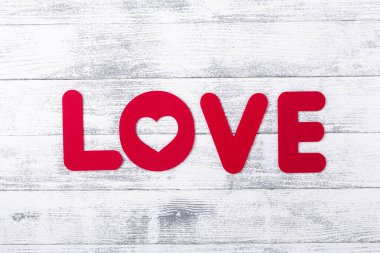 Beyaz ahşap arka planda Aşk kelimesi. Kırmızı tekstil harfleri.