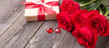 Kırmızı güller ve hediye kutusu gri ahşap masada. Tebrik kartı. Uzayı metin için kopyala. Yatay Pankart