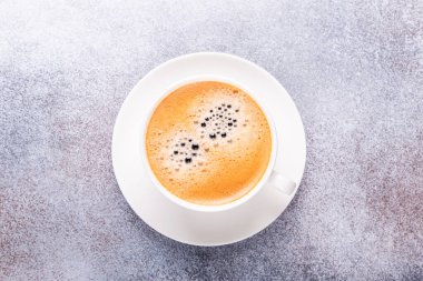 Taş masada beyaz bir fincan kahve. Üst görünüm