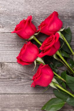 Gri ahşap masada kırmızı güller. Sevgililer Günü tebrik kartı. Üst Manzara. Boşluğu kopyala