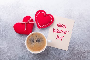 Sevgililer Günü tebrik kartı. Taş zeminde kahve fincanı ve tekstil kalpleri. Üst görünüm