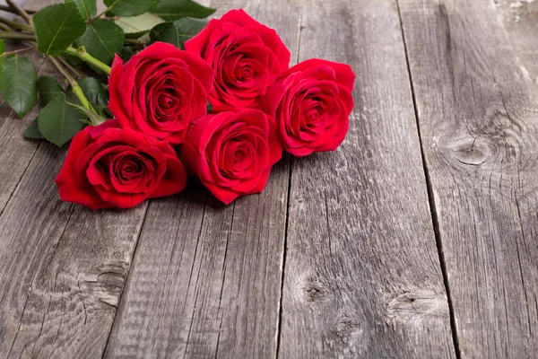 Röda rosor blommar på grått träbord. Gratulationskort. Kopiera utrymme för text — Stockfoto
