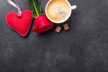 Sevgililer Günü tebrik kartı. Kahve fincanı, kırmızı güller ve taş zeminde tekstil kalpleri. Üst görünüm